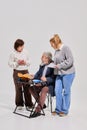 Three elderly students, man and women with books and notes interacting during classroom activity against white studio Royalty Free Stock Photo