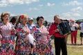 Three elderly women in colorful dresses sing next to the harmonist at the Karatag music festival. Royalty Free Stock Photo