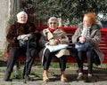 Three elderly women sitting on the red bench under the tree in an inner atmospheric courtyard.