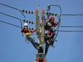Three Electricians Installing Electrical Equipment on an Electric Pole