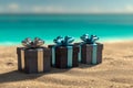 Three elegant black gift boxes with shiny silver and blue ribbons placed on sandy beach with turquoise ocean in soft focus Royalty Free Stock Photo