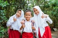 three elementary students standing with thumbs up and embracing each other Royalty Free Stock Photo