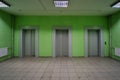 Three elevator doors in a residential building. Wide-angle view of modern elevators with doors, green walls. Elevators in the