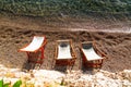 Three empty beach chairs on a pebbled shore, facing the calm, clear waters of the ocean on a sunny day. Royalty Free Stock Photo