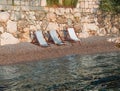 Three empty beach chairs resting by the calm seaside, inviting a peaceful moment by the shore. Royalty Free Stock Photo