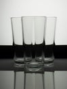 Three empty glasses on a blackand white background with reflecti