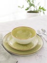 Three empty green plates with silver cutlery and tablecloth on white marble table in front of window Royalty Free Stock Photo
