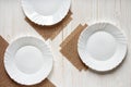 three empty plates on burlap kitchen napkins on white wooden table, top view Royalty Free Stock Photo