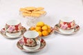 Three empty porcelain teacups with floral pattern, biscuits and plate with wild apricots