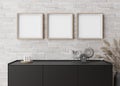 Three empty square picture frames on white brick wall in modern living room. Mock up interior in minimalist Royalty Free Stock Photo