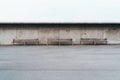 Three empty street outdoor benches with a concrete wall behind