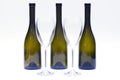 Three empty upturned wine bottles and two glasses on a white background