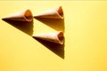 Three empty waffle cups for ice cream on a yellow background in bright sunlight and crisp, hard shadows. Copy space