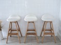 Three empty white seat wooden bar stool chairs on vintage tiles wall background, loft style cafe deco. Royalty Free Stock Photo