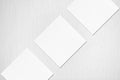 Three empty white square business card mockups lying diagonally on grey background Royalty Free Stock Photo