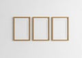 Three empty wooden picture frames arranged horizontally on a plain white wall Royalty Free Stock Photo