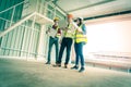 Three engineer male and female discussing on document and computer in a building construction site