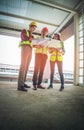 Three engineer male and female discussing on document and computer in a building construction site