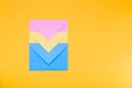Three envelopes of yellow, blue and pink colors nested in each other lie on a yellow background copy space top view, minimalism co