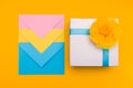 Three envelopes of yellow, blue and pink colors nested in each other lie on a yellow background next to a shiny gift box with a ye