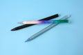 Three erasable pens on light blue background, top view