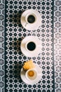 Three espresso coffee cups and saucers on pattern table cloth Royalty Free Stock Photo