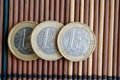 Three euro coins lie on wooden bamboo table in a row Denomination is one euro