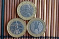 Three euro coins lie on wooden bamboo table in a row Denomination is two euro - back side