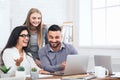 Three excited employees receiving good news on laptop