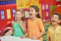 Three excited kids in playroom.