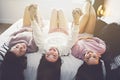 Three excited teenager girls having fun together enjoying laze leisure time on bed