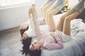 Three excited teenager girls having fun together enjoying laze leisure time on bed