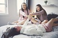 Three excited teenager girls having fun together enjoying laze leisure time on bed