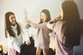 Three excited teenager girls having fun together enjoying laze leisure time with pillow fight