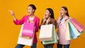 Three Excited Women With Shopping Bags Pointing Fingers, Studio Shot