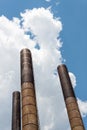 Three extremely tall smokestacks seen from below against a blue sky with clouds, hopeful industrial image with creative copy space