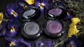 three eyeshades sitting on top of a table next to purple flowers and purple pansies on a black surface with yellow and purple