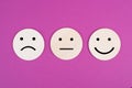 Three faces, smiling, sad in different colors on a pink background, copy space, rating, communication Royalty Free Stock Photo