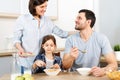 Three family members have delicious healthy breakfast at kitchen, eat cornflakes with milk, enjoy togetherness and