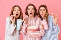 Three fascinating young girls 20s in colorful homewear eating po Royalty Free Stock Photo