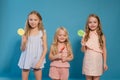 Three fashionable little girls eat candy lollipop