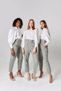 Three fashionable stylish young women in office style clothes posing over light background. Concept of beauty, fashion Royalty Free Stock Photo