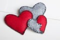 Three felt hearts on a white wooden background,