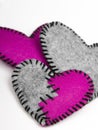 Three felt hearts on a white wooden background