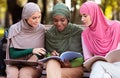 Three Female Arab Students Learning Together Reading Books Sitting Outdoors Royalty Free Stock Photo