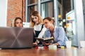 Three female college students doing homework together using one laptop and lecture notes sitting at desk in study room Royalty Free Stock Photo