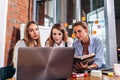 Three female college students studying together using laptop and lecture notes sitting at desk in study room Royalty Free Stock Photo