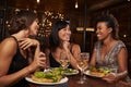 Three female friends eating dinner together at a restaurant