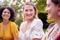 Three Female Friends Sitting Outdoors Together And Catching Up In Summer Garden At Home 