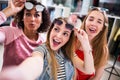 Three female friends taking selfie making faces raising sunglasses in clothing and accessories outlet